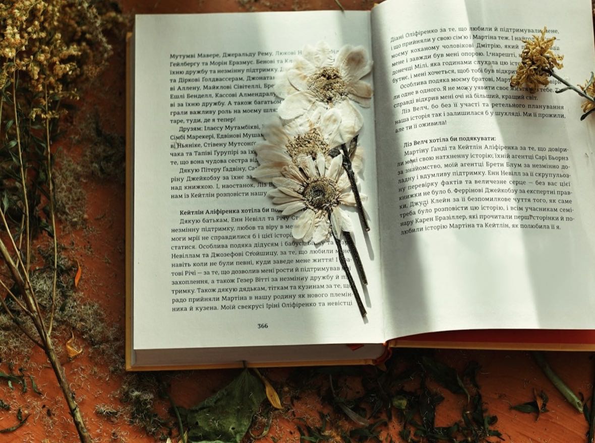 Flowers pressed between the pages of a book, surrounded by drying botanicals